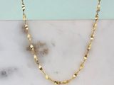 un gros plan d'un collier en or posé sur une surface en marbre