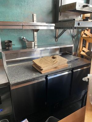 stainless steel counter top with a cutting board on it in a commercial kitchen