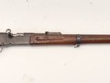 Un vieux fusil est posé sur une surface blanche, près d'un mur.