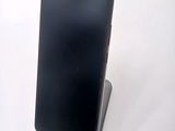 a black cell phone on a stand on a white surface