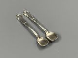 pair of silver spoons on a table with a gray background
