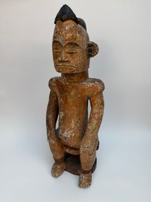 une vieille statue en bois d'un homme avec un chapeau sur la tête