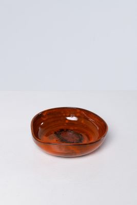 un bol marron posé sur une table blanche, sur fond blanc