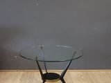 a glass coffee table with a black base and a wooden base