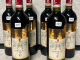 six bottles of wine are lined up on a counter