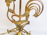 a brass rooster on a stand with a light on it