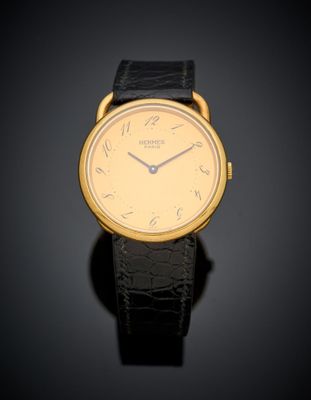 a close up of a gold wrist watch with a black leather strap