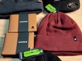several different hats are on a wooden table with tags on them