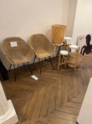 plusieurs chaises et tabourets en osier dans une pièce avec un parquet