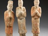 three ancient figurines of three men standing next to each other