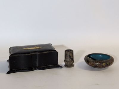 une petite boîte noire, un petit bol bleu et une petite tasse en argent