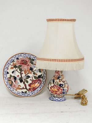 une lampe posée à côté d'une assiette décorée de fleurs