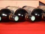 several bottles of wine are lined up on a red cloth