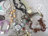 many different necklaces and bracelets laid out on a table