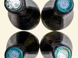 four bottles of wine are lined up in a row on a white surface