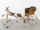 a toy horse pulling a carriage with a horse on it