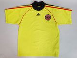 a yellow soccer jersey with a black collar and a red stripe on the chest