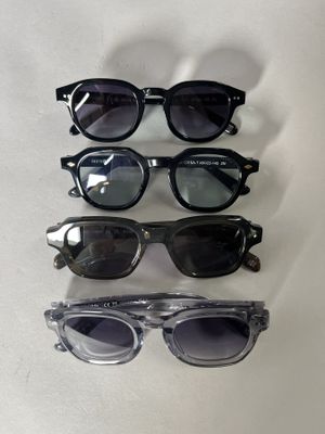 four pairs of sunglasses are lined up on a white surface