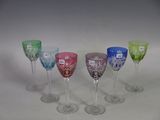 several different colored wine glasses are lined up on a white surface