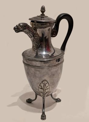 a silver tea pot on a stand with a dragon head on it