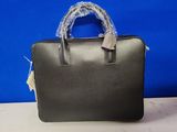 un sac à main noir avec une poignée bleue posé sur une table blanche