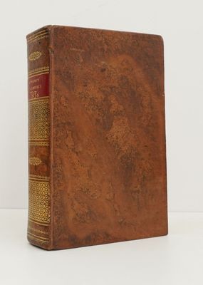 un vieux livre à la couverture marron posé sur une table blanche