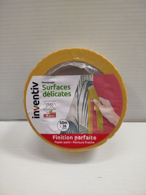 un ruban adhésif jaune sur une surface blanche, avec une main tenant un morceau de ruban adhésif