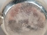 a close up of a silver pocket watch on a white surface
