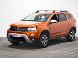 La Dacia orange est garée dans une pièce au sol carrelé en damier.
