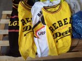 des t-shirts jaunes et noirs posés sur une palette en bois, à côté d'un jean bleu