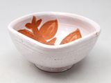 un petit bol blanc orné de feuilles orange