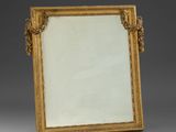 a gold framed mirror with a decorative design on the edge