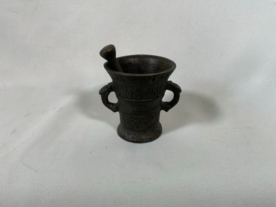 un vase noir contenant une cuillère, posé sur une surface blanche