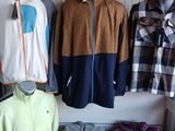 Plusieurs vêtements pour hommes sont présentés sur un portemanteau dans un magasin de vêtements