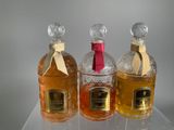 three bottles of perfume sitting on top of a clear table