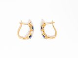 une paire de boucles d'oreilles créoles en or et saphir sur fond blanc