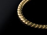 a close up of a gold bracelet on a black surface