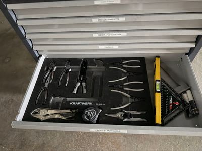 une boîte à outils posée par terre et contenant de nombreux outils