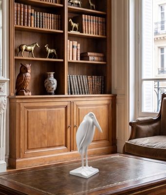 a white bird sitting on a coffee table in front of a bookshelf
