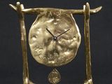 a gold clock that is sitting on a stand