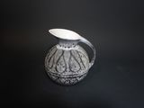 a black and white vase with a spoon in it