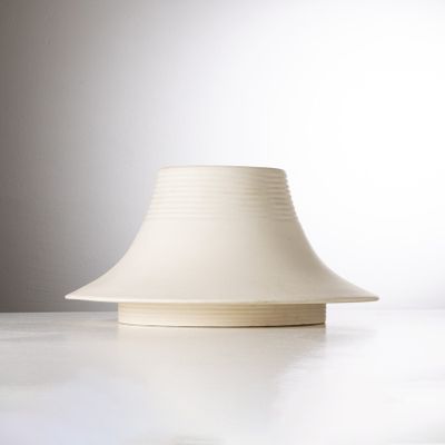 un vase blanc posé sur une table à fond blanc