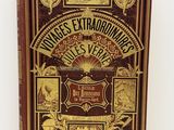 an old book with gold lettering on it sitting on a white surface