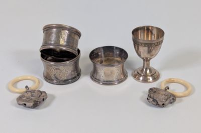 une coupe en argent et d'autres objets en argent posés sur une surface blanche