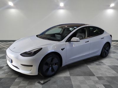 the white tesla model 3 is parked in a large room