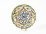 une assiette décorative posée sur un socle, sur une surface blanche