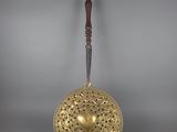 une cloche ancienne en laiton avec une poignée en bois sur fond gris