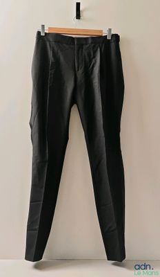 un pantalon en cuir noir suspendu à un cintre devant un mur blanc