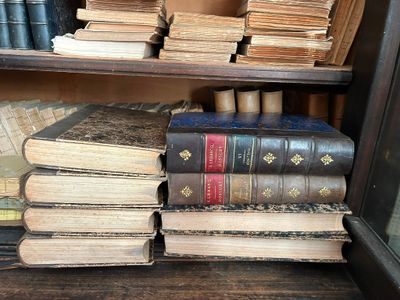 de nombreux livres anciens empilés sur une étagère dans une bibliothèque