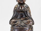 une image représentant une statue d'une personne assise sur un rocher